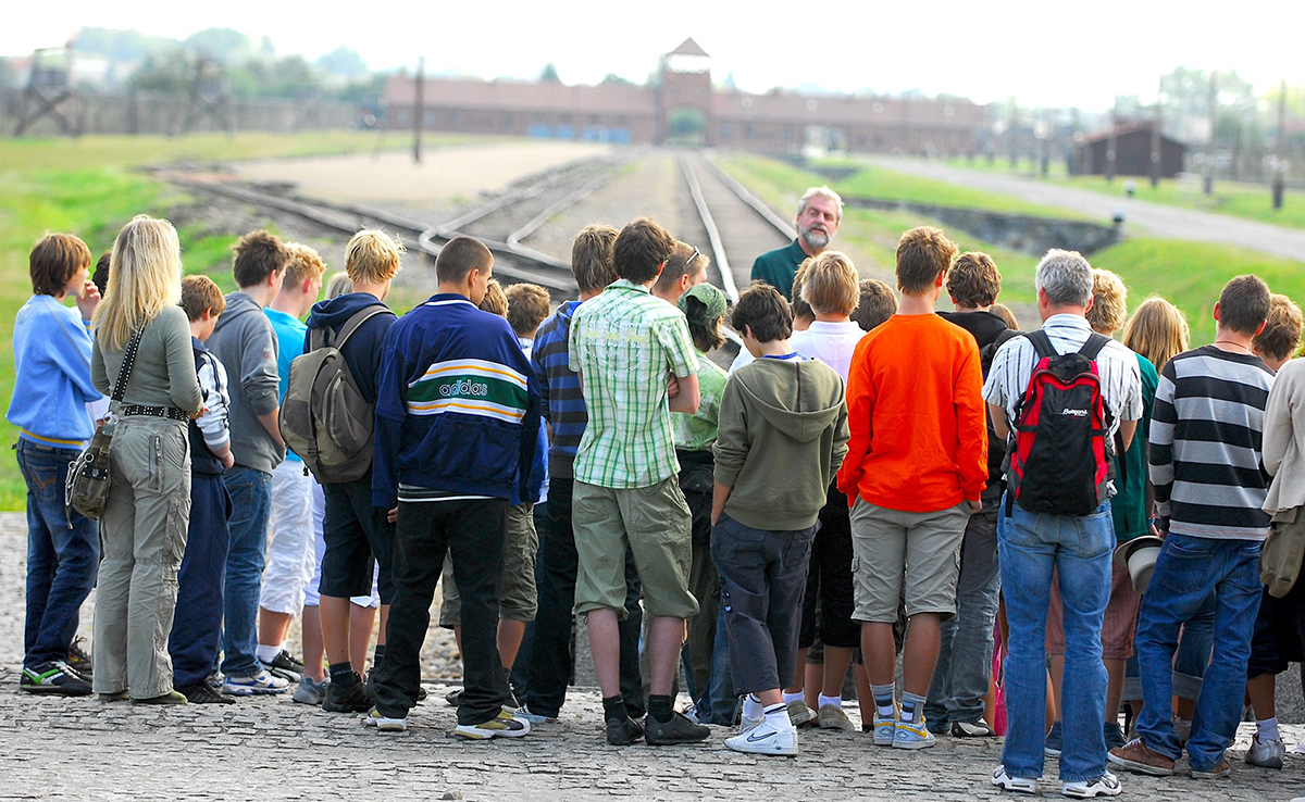 Ungdomsgruppe med reiseleder ved jernbanesporet inn mot Auschwitz-Birkenau